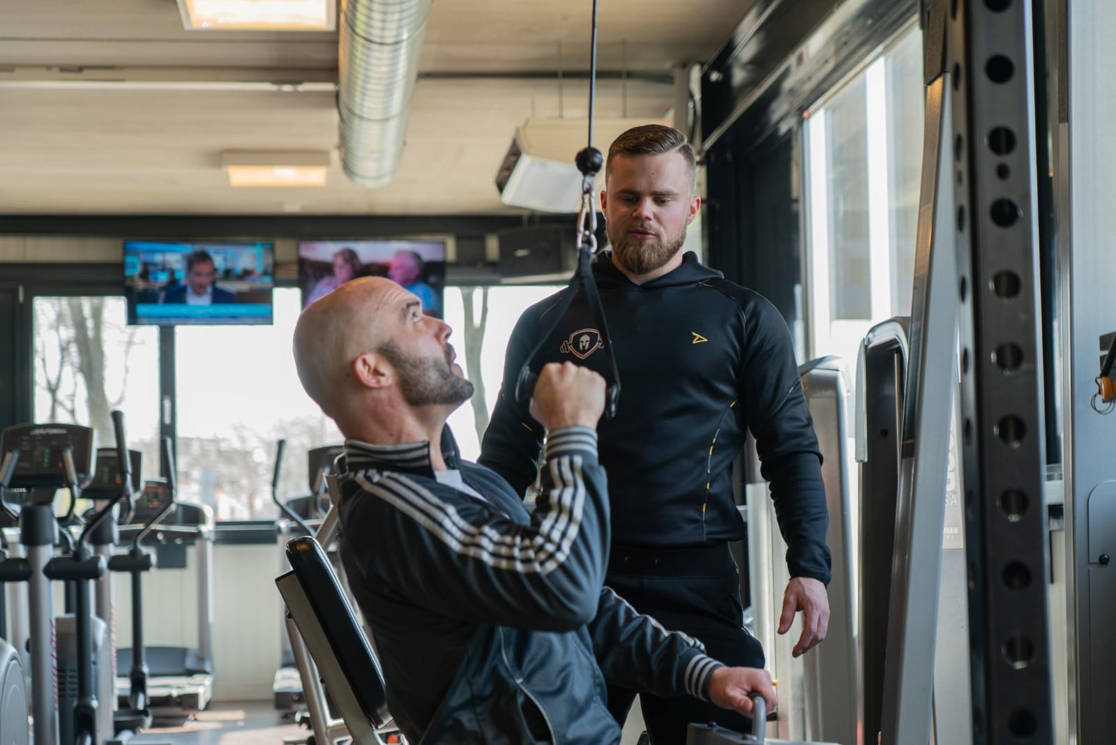 Simon begeleidt een klant tijdens een training in de sportschool
